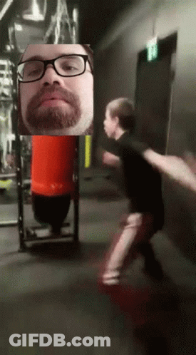 Man With Glasses And Beard In Front Of Red Bag GIF