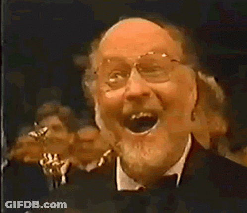 Man With Glasses And Beard Laughing Before Crowd GIF