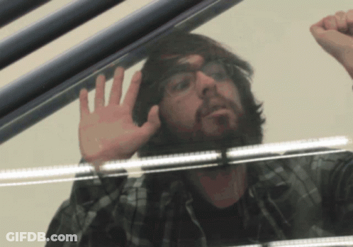 Man With Glasses And Beard Looking Through Glass Door GIF