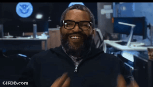 Man With Glasses And Beard Smiling Before U.S. Department Of Homeland Security Sign GIF