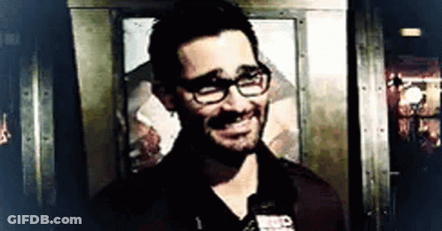 Man With Glasses And Beard Smiling In Front Of Door GIF