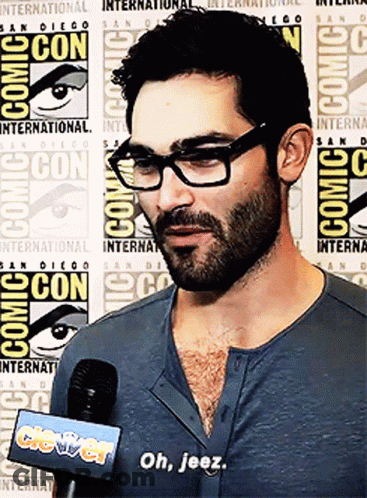 Man With Glasses And Beard Talking Into Microphone At Comic Con GIF