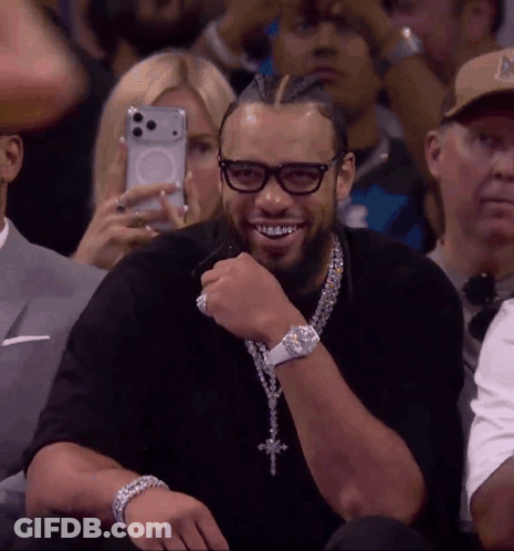 Man With Glasses And Cross Necklace Smiling In Stands GIF