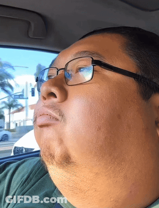 Man With Glasses And Green Shirt Looks Out Window GIF