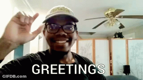 Man With Glasses And Hat Saying Greetings In Front Of Ceiling Fan GIF
