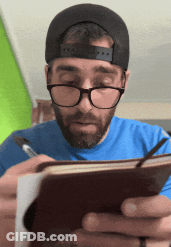 Man With Glasses And Hat Writing In Notebook GIF