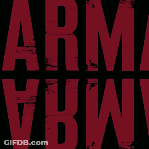 Man With Glasses And Lettered Shirt Looking At Camera GIF