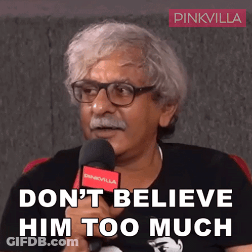 Man With Glasses And Mustache Holding Microphone Says Don't Believe Him Too Much GIF