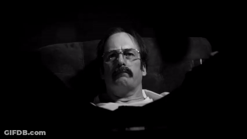Man With Glasses And Mustache Laying In Chair In Dark Room GIF