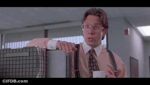 Man With Glasses And Suspenders Leaning On Cubicle With Coffee GIF