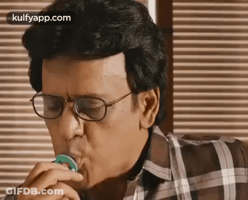Man With Glasses Eating Green Candy At Table GIF