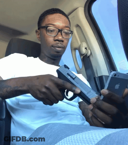 Man With Glasses Holding Gun Looking At Phone GIF