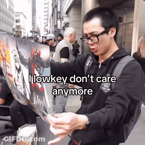 Man With Glasses Holding Sign Saying I Lowkey Don't Care Anymore GIF