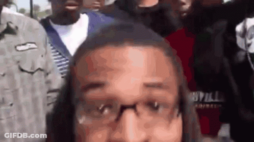 Man With Glasses In Crowd Looking At Camera GIF