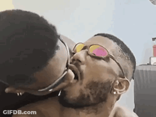 Man With Glasses Kissing Another Man On Cheek GIF