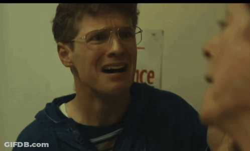 Man With Glasses Making Funny Face In Front Of Ance Sign GIF
