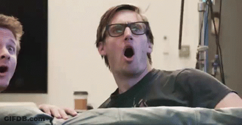 Man With Glasses On Couch Mouth Open Another Man Watching GIF