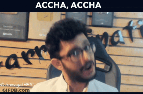 Man With Glasses Sitting In Front Of Accha Accha Wall GIF
