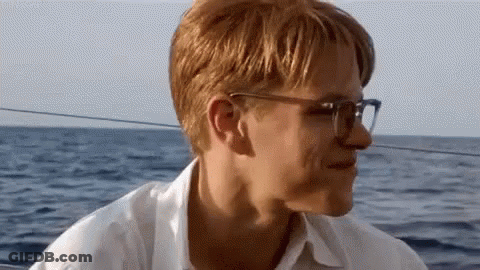 Man With Glasses Sitting On Boat Looking At Ocean GIF