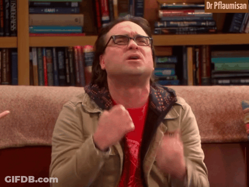 Man With Glasses Sitting On Couch In Front Of Bookshelf Dr Pflaumisan GIF