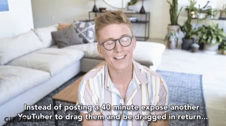 Man With Glasses Smiling In Front Of Couch And Coffee Table GIF
