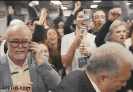 Man With Glasses Talking On Cell Phone In Crowd GIF