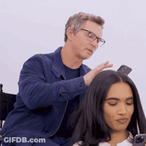 Man With Glasses Touching Woman's Hair Holding Cell Phone GIF