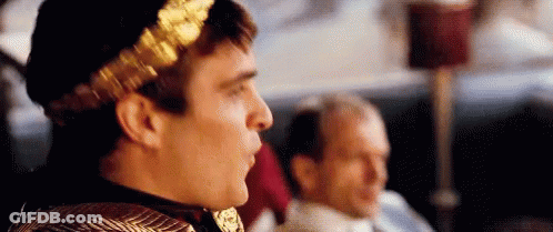 Man With Gold Laurel Wreath Sitting Beside Another Man GIF