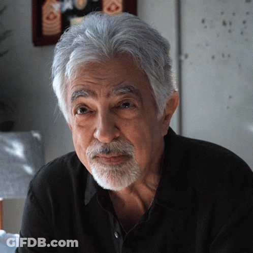 Man With Gray Hair And Beard Looks At Camera GIF