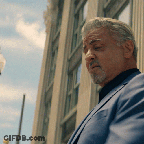 Man With Gray Hair And Beard Stands In Front Of Building GIF