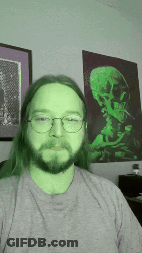 Man With Green Hair And Glasses In Front Of Skull Painting GIF