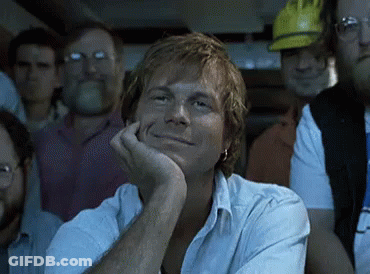 Man With Hand On Chin Smiling In Crowd GIF