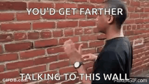 Man With Hands Up In Front Of Brick Wall GIF