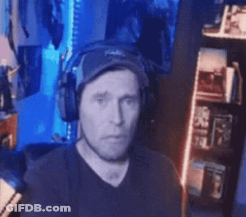 Man With Headphones And Hat Sitting In Front Of Bookshelf GIF
