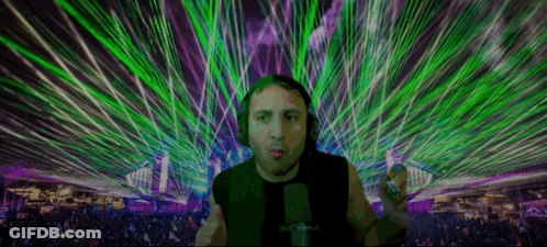 Man With Headphones At Microphone In Front Of Crowd With Green And Purple Lasers GIF