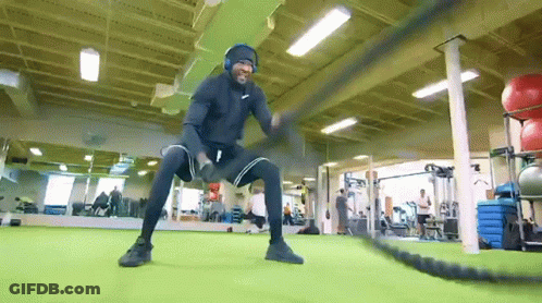 Man With Headphones Doing Battle Rope Exercises GIF
