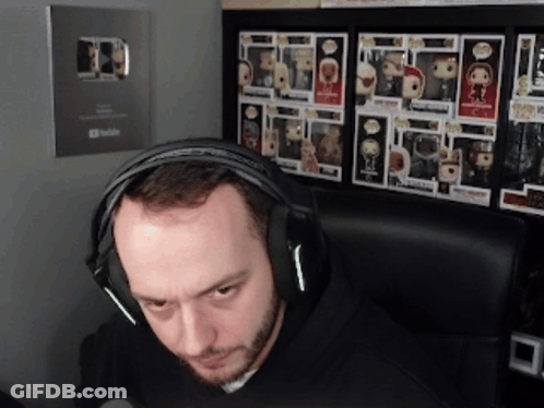 Man With Headphones In Front Of Funko Pop Wall GIF