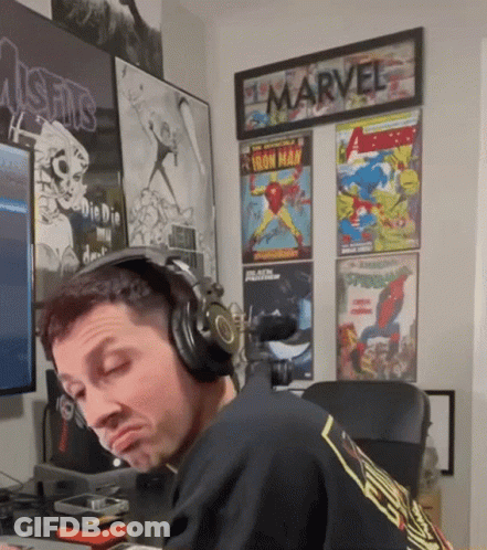 Man With Headphones In Front Of Marvel Posters GIF