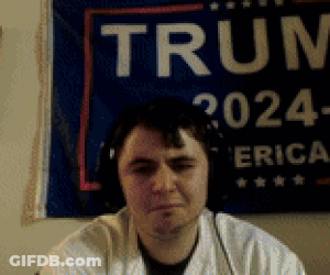 Man With Headphones In Front Of Trump Sign GIF