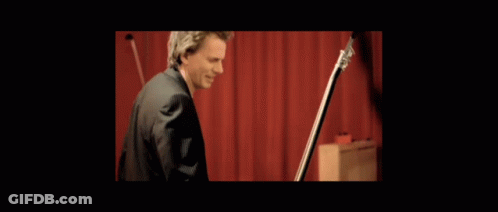 Man With Headphones Playing Guitar At Red Wall GIF