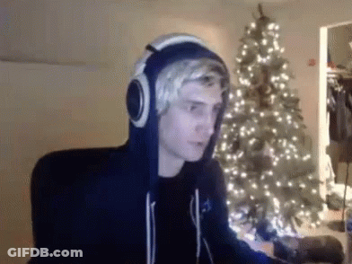 Man With Headphones Sitting By Christmas Tree GIF