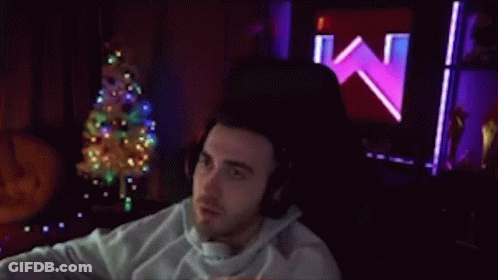 Man With Headphones Sitting By Christmas Tree GIF