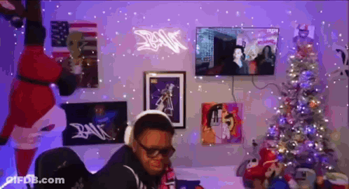 Man With Headphones Sitting By Christmas Tree GIF