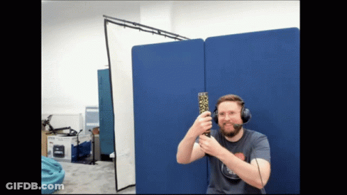 Man With Headset Holding Remote In Front Of Blue Wall GIF