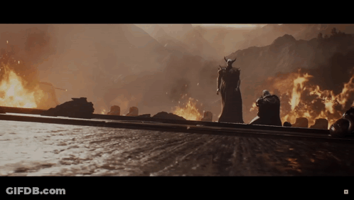 Man With Horns Statue In Front Of Burning Mountain GIF