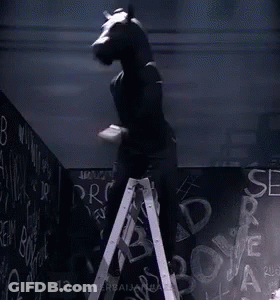 Man With Horse Head Standing On Ladder In Front Of Blackboard GIF