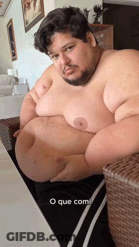 Man With Large Belly Sitting On Wicker Chair Saying O Que Comi GIF