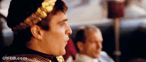 Man With Laurel Wreath Sitting Next To Man GIF