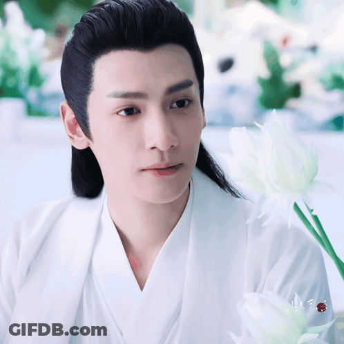 Man With Long Black Hair Holding White Flower GIF