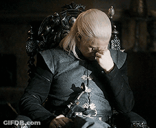 Man With Long Blonde Hair Sitting In Chair Hand On Face GIF